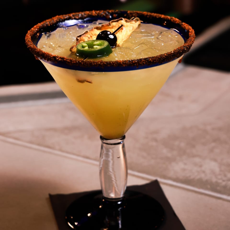 Xochitl Cocina & Tequila's margarita with a chili-lime rim, pineapple, cherry, and jalapeño garnish.