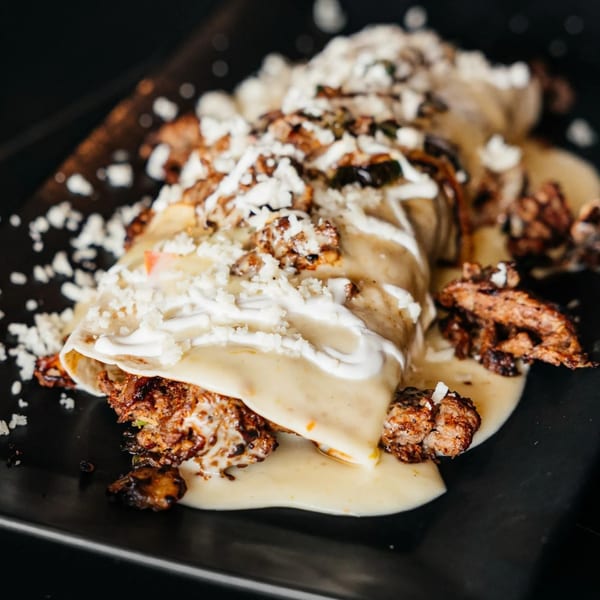 Xochitl Cocina & Tequila's enchiladas, topped with creamy sauce, sour cream, and crumbled cheese.