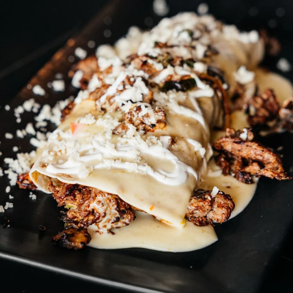 Xochitl Cocina & Tequila's enchiladas, topped with creamy sauce, sour cream, and crumbled cheese.
